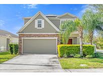 Charming two-story home featuring a stone and siding facade, manicured lawn, and attached two-car garage at 4432 Desert Rose Ave, Kissimmee, FL 34746