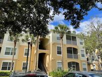 Exterior view of a multi-story condo building with balconies and palm trees at 6100 Stevenson Dr # 207, Orlando, FL 32835
