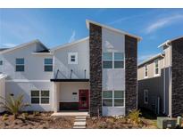 Stylish two-story home with a modern facade, stone accents, and a vibrant red front door at 1070 Splash Shot Pl, Davenport, FL 33896