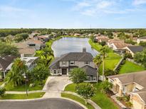 A stunning aerial view of a grey home, showcasing the backyard lake and lush green landscaping around the property at 218 Pebblerock Ct, Orlando, FL 32828