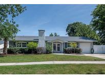 Charming one story home boasts a well-manicured lawn, mature landscaping, and neutral color palette at 2325 E Harding Street, Orlando, FL 32806