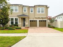 Two-story home featuring a two-car garage, brick driveway, and well-maintained landscaping at 5107 Longmeadow Park St, Orlando, FL 32811