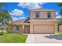 Charming two-story home featuring a manicured lawn, two-car garage, and inviting curb appeal at 5200 Sunset Canyon Dr, Kissimmee, FL 34758