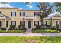 Charming two-story townhome featuring a welcoming entrance with black shutters and a well-manicured lawn at 5235 Keenes Pheasant Dr, Windermere, FL 34786