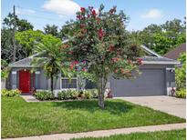 Charming single-story home boasts a red door, well-manicured lawn, and mature landscaping at 632 Bridge Creek Blvd, Ocoee, FL 34761