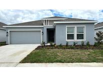 Charming single-story home with a gray stucco exterior, well-manicured lawn, and an attached garage at 680 Sand Pine Ln, Haines City, FL 33844