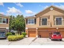 Townhome featuring a tan exterior, balcony, attached garage, and well-maintained landscaping at 1210 San Jacinto Cir, Sanford, FL 32771