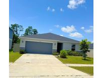 A charming single-story home featuring a well-maintained lawn and a two-car garage on a sunny day at 1557 Venice Ln, Davenport, FL 33896