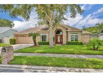 Charming brick home featuring a beautiful front yard with mature landscaping and a stately tree at 2265 Turnberry Dr, Oviedo, FL 32765