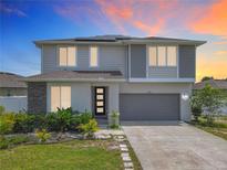 Beautiful two-story home featuring stone accents, a modern front door, lush landscaping, and a spacious two-car garage at 242 White Heron Way, St Cloud, FL 34772