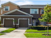 Townhouse exterior featuring attached garages, neat landscaping, and coordinated color schemes under a bright sky at 2918 Rodrick Cir, Orlando, FL 32824