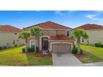 Charming two-story home featuring a Spanish tile roof, arched entryway, and tropical landscaping at 381 Cabello Dr, Davenport, FL 33837
