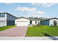 Charming one-story home with a two-car garage, brick driveway, manicured lawn, and lovely landscaping at 4709 Jasmine Cir, Leesburg, FL 34748