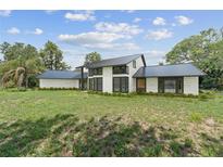 Modern home showcasing a well-manicured lawn, textured white exterior, and sleek black accents at 8735 Rancho Ct, Orlando, FL 32836