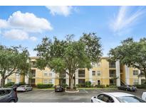 View of the condo building with parking lot and landscaping, under a sunny sky with scattered clouds at 1125 Lake Shadow Cir # 5109, Maitland, FL 32751