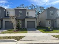 Modern townhome featuring a gray exterior, single-car garage, and well-maintained lawn at 1205 Southstation Pl # 208, Orlando, FL 32809