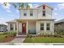 Charming two-story home with a welcoming porch and vibrant red door, complemented by lush landscaping at 13208 Leggett Aly, Orlando, FL 32827