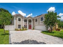 Two-story home showcasing a red front door, manicured landscaping, and a paved driveway, all under a sunny sky at 1706 Cheltenborough Dr, Orlando, FL 32835