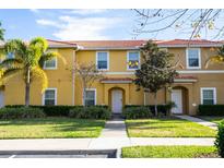 Charming townhome with vibrant yellow exterior, red tile roof, and well-manicured landscaping at 3065 Yellow Lantana Ln, Kissimmee, FL 34747