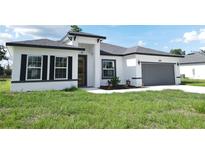 Charming single-story home features a two-car garage, crisp white stucco, and black accents at 3159 Sw 127Th Lane Rd, Ocala, FL 34473