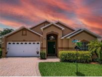 Charming single-Gathering home with a well-manicured lawn, brick driveway, and beautiful landscaping at 456 Old Bridge Cir, Davenport, FL 33897