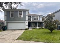 Two-story home featuring gray siding, white trim, an attached garage, and a well-maintained front yard at 512 Flower Fields Ln, Orlando, FL 32824