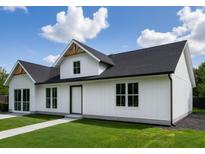 Modern farmhouse with white siding, black roof, and well-manicured lawn presents a striking exterior at 9659 Midway Rd, Haines City, FL 33844