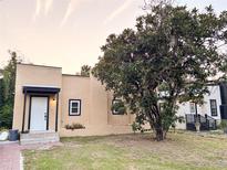 Charming beige home featuring a large tree, a white front door and black window trim at 112 Avocado Ave, Sanford, FL 32771