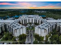 Stunning aerial view of the resort-style condo community with beautiful landscaping, lakes, and a vibrant sunset backdrop at 14501 Grove Resort Ave # 3239, Winter Garden, FL 34787