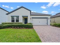 Charming single-story home with a well-manicured lawn, brick driveway, and a two-car garage at 2210 Romanum Dr, Winter Garden, FL 34787