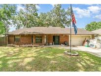 Charming single-story brick home featuring a well-maintained lawn, flag, and attached garage at 236 Longhorn Dr, Apopka, FL 32712
