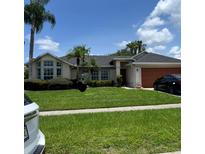 Inviting single-story home with lush landscaping, mature palms and two car garage at 2421 Queenswood Cir, Kissimmee, FL 34743