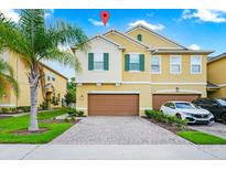 Two-story home featuring a two-car garage, a well-maintained lawn, and a charming palm tree in the front yard at 10070 Red Eagle Dr, Orlando, FL 32825