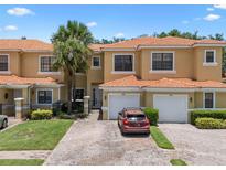 Inviting townhome exterior with a red tile roof, brick driveway, and lush landscaping, including a palm tree at 1434 Pacific Rd, Kissimmee, FL 34759