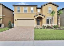 Welcoming two-story home showcasing well-manicured landscaping, brick-paved driveway, and covered front porch at 1606 Lima Ave, Kissimmee, FL 34747
