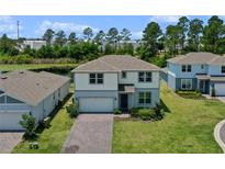 Charming two-story home featuring a brick driveway, manicured lawn, and serene water view at 17319 Million Lakes Ct, Clermont, FL 34714