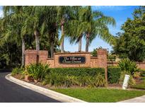 Landscaped entrance to The Villas at Chase Groves with brick sign and mature palm trees at 2011 Crestdale Ln, Lake Mary, FL 32746