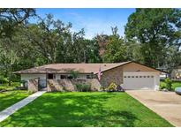 Charming single-story home featuring a brick facade, lush green lawn, and mature trees under a bright, sunny sky at 203 N Sweetwater Blvd, Longwood, FL 32779
