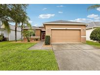 Inviting single-story home featuring a two-car garage and well-manicured front lawn with mature palm trees at 2628 Balforn Tower Way, Winter Garden, FL 34787