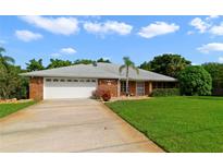 Charming single-story brick home with a well-manicured lawn and a two-car garage with beautiful landscaping at 428 N Pine Meadow Dr, Debary, FL 32713