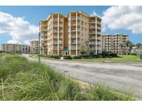 Beautiful yellow condominium building featuring multiple balconies with manicured landscaping and blue skies at 4650 Links Village Dr # B103, Ponce Inlet, FL 32127