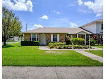 Charming brick home featuring a well-maintained lawn, lush landscaping, and welcoming front entrance at 901 Illinois Ave, St Cloud, FL 34769