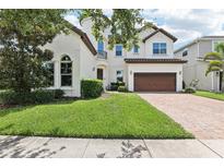 Charming two-story stucco home featuring a tile roof, well-manicured lawn and attached two-car garage at 9207 Busaco Park Way, Winter Garden, FL 34787