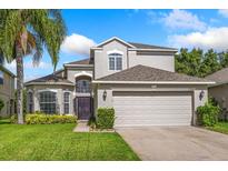 Charming two-story home with lush green lawn, landscaped garden, and attached two-car garage at 9966 Hidden Dunes Ln, Orlando, FL 32832