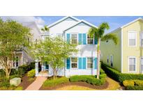 Charming two-story home featuring bright white siding, blue shutters, and a lush, landscaped front yard at 1545 Fairview Cir, Reunion, FL 34747