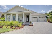 Charming home featuring a manicured lawn, brick paved driveway, and a welcoming front porch with classic columns at 1774 Pasture Loop, Oviedo, FL 32765