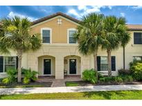 Charming townhouse exterior featuring a well-maintained facade and tropical landscaping with palm trees at 1909 Majorca Dr, Kissimmee, FL 34747