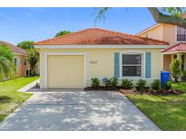 Charming single-story home featuring a red tile roof, light yellow siding, and a single-car garage at 2422 Condado Ct, Kissimmee, FL 34743