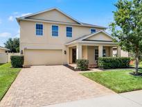 Charming two-story home featuring a brick driveway, manicured landscaping, and attached two-car garage at 2432 Riviera Ln, Minneola, FL 34715