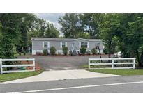 Charming single-story home with gray siding, a graveled yard, and a white picket fence at 31701 State Road 44 Sr-44, Eustis, FL 32736